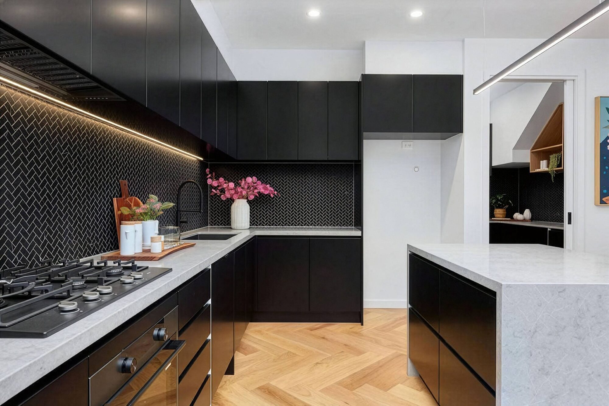 Custom home kitchen with black cabinetry, stone island and herringbone timber flooring