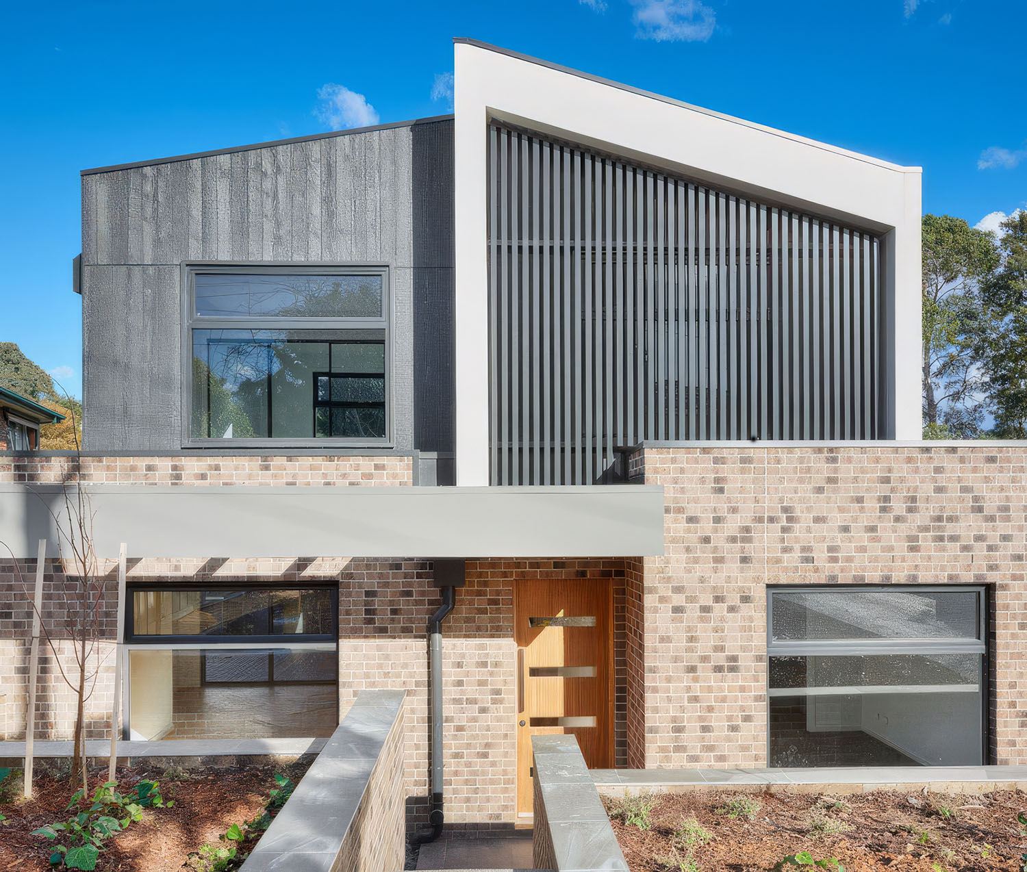 Modern dual-occupancy facade with brick and privacy screens in Bulleen